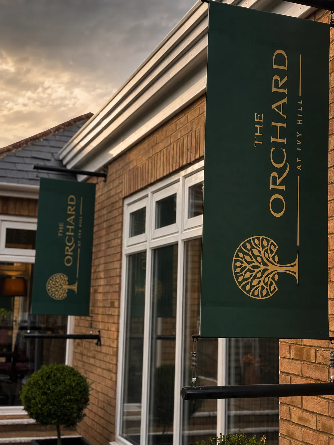 Green and gold The Orchard banners hanging outside the restaurant entrance